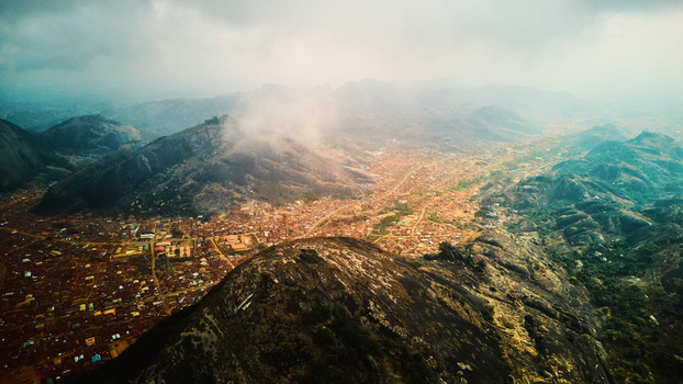 Aerial view of the undulating rocky terrain meeting the clustered buildings under a blanket of soft mist Idanre Ondo Nigeria. Aerial view of the undulating rocky terrain meeting the clustered buildings under a blanket of soft mist Idanre Ondo Nigeria.