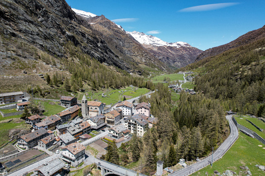 Aerial view of the alpine village of Valgrisenche with stone houses and a church tower nestled in a deep valley surrounded by rugged mountains Valgrisenche Aosta Valley Italy.