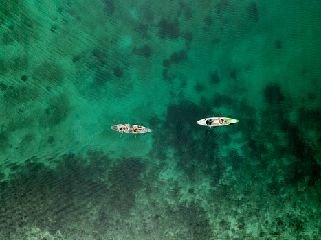 Aerial view of two kayaks with people paddling through the clear turquoise waters of Sugba Lagoon in Del Carmen Caraga Philippines. Aerial view of two kayaks with people paddling through the clear turquoise waters of Sugba Lagoon in Del Carmen Caraga Philippines.
