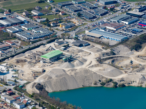 Aerial view of an industrial area with a quarry and a bright blue lake contrasting with the surrounding buildings Sausheim Grand Est France.