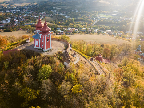 Aerial view of Stiavnicka kalvaria a historic pilgrimage site with a red and white chapel on a hill surrounded by autumn forests and Banska Stiavnica Banskobystricky kraj Slovakia. Aerial view of Stiavnicka kalvaria a historic pilgrimage site with a red and white chapel on a hill surrounded by autumn forests and Banska Stiavnica Banskobystricky kraj Slovakia.