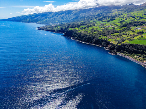 Aerial view of the rugged coastline meeting the deep blue sea showcasing the lush green landscapes of Pico Azores Portugal. Aerial view of the rugged coastline meeting the deep blue sea showcasing the lush green landscapes of Pico Azores Portugal.