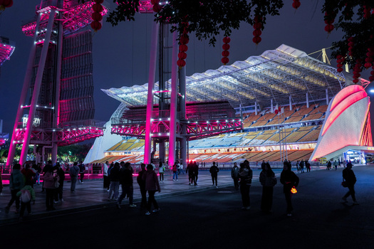 Guangzhou China 24 February 2024 View of the illuminated Haixinsha Asian Games Park stadium at night with crowds of people walking in the foreground under red lanterns. Guangzhou China 24 February 2024 View of the illuminated Haixinsha Asian Games Park stadium at night with crowds of people walking in the foreground under red lanterns.