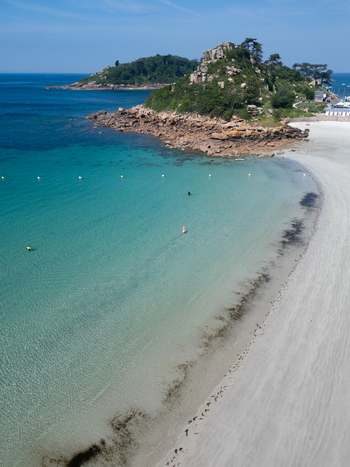 Aerial view of the turquoise waters and white sandy beach with people swimming in the clear sea in Trebeurden Brittany France. Aerial view of the turquoise waters and white sandy beach with people swimming in the clear sea in Trebeurden Brittany France.