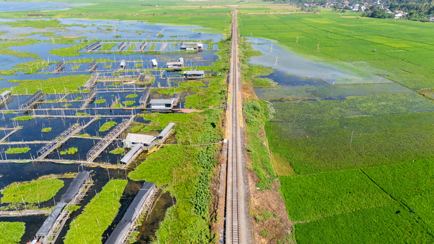 Aerial view of Lake Rawa Pening with a railway track dividing the water and lush green rice fields in Waduk Rawapening Central Java Indonesia. Aerial view of Lake Rawa Pening with a railway track dividing the water and lush green rice fields in Waduk Rawapening Central Java Indonesia.