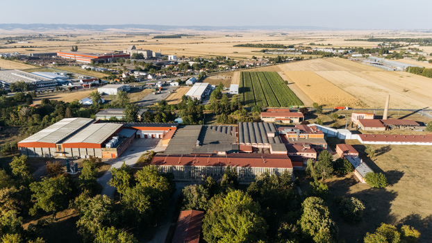 Aerial view of an industrial facility with large factory buildings and metal roofs surrounded by agricultural fields and trees in Sremska Mitrovica Vojvodina Serbia. Aerial view of an industrial facility with large factory buildings and metal roofs surrounded by agricultural fields and trees in Sremska Mitrovica Vojvodina Serbia.