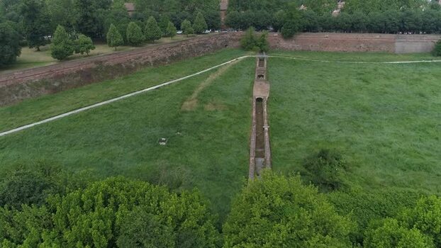 Aerial view of the historic brick city walls and lush green moat area with walking paths and dense trees in Ferrara Emilia Romagna Italy. Aerial view of the historic brick city walls and lush green moat area with walking paths and dense trees in Ferrara Emilia Romagna Italy.