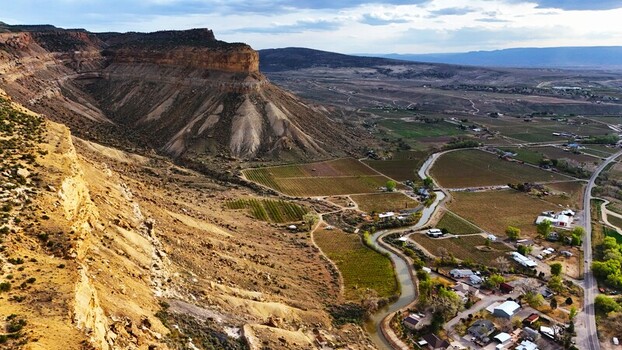 Aerial view of the dramatic canyon walls contrasting with the verdant fields and winding river below Palisade Colorado USA. Aerial view of the dramatic canyon walls contrasting with the verdant fields and winding river below Palisade Colorado USA.