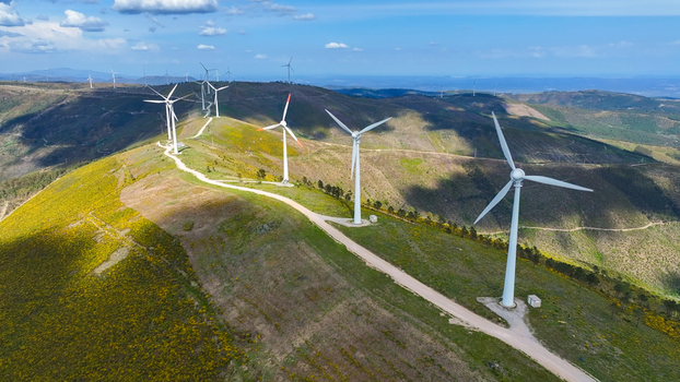 Aerial view of wind turbines situated on a grassy hill with yellow wildflowers under a blue sky in Lisbon Lisbon Portugal. Aerial view of wind turbines situated on a grassy hill with yellow wildflowers under a blue sky in Lisbon Lisbon Portugal.