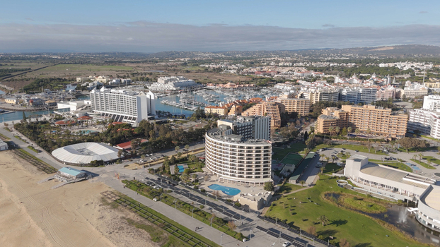 Aerial view of the Vilamoura marina and resort area featuring modern hotels swimming pools and boats docked in the harbor in Quarteira Faro District Portugal.