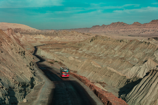 View of a bus traveling along the winding Makran Coastal Highway through the rugged arid desert mountains of Balochistan Pakistan.
