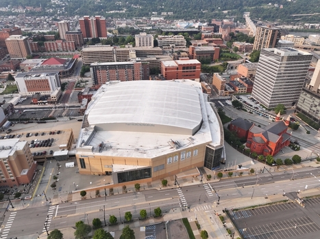 Pittsburgh Pennsylvania United States 26 July 2026 Aerial view of PPG Paints Arena surrounded by urban buildings streets and a historic red brick church.