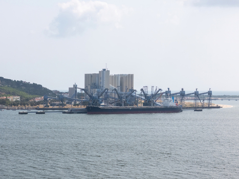 Aerial view of a large cargo ship docked at the grain silos in the harbor with industrial loading equipment in Lisbon Lisbon Portugal.