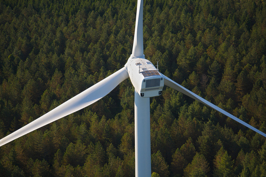 Aerial view of a solitary wind turbine standing tall against a dark green forest its white blades contrasting sharply against the verdant backdrop Salles Curan Occitanie France. Aerial view of a solitary wind turbine standing tall against a dark green forest its white blades contrasting sharply against the verdant backdrop Salles Curan Occitanie France.