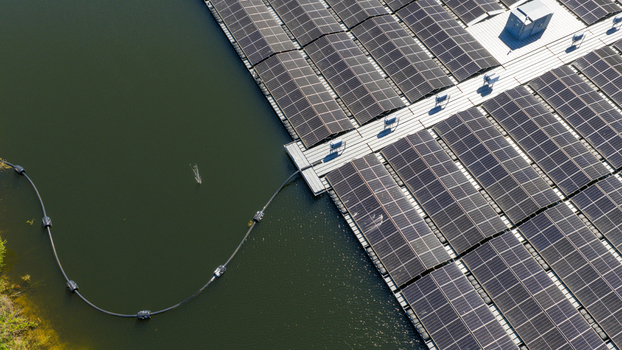 Aerial view of a floating solar farm with rows of photovoltaic panels and white walkways on calm water in Zwolle Overijssel Netherlands. Aerial view of a floating solar farm with rows of photovoltaic panels and white walkways on calm water in Zwolle Overijssel Netherlands.