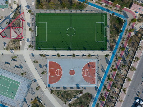 Aerial view of a modern sports park featuring a soccer field a basketball court and a tennis court surrounded by walking paths and landscaping in Berat Berat County Albania.