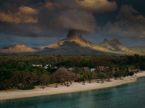 Aerial view of the dramatic Moka Range mountains rising behind a white sand beach and turquoise lagoon under a stormy sky in Mauritius Moka District Mauritius. Aerial view of the dramatic Moka Range mountains rising behind a white sand beach and turquoise lagoon under a stormy sky in Mauritius Moka District Mauritius.