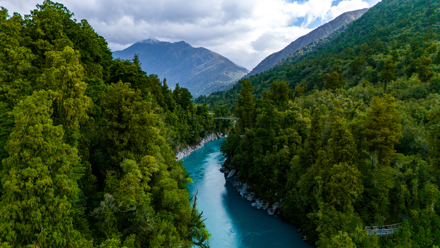 Aerial view of the Hokitika Gorge s turquoise waters carve a path through the dense vibrant green forest under a sky of soft diffused light Hokitika Gorge West Coast Region New Zealand. Aerial view of the Hokitika Gorge s turquoise waters carve a path through the dense vibrant green forest under a sky of soft diffused light Hokitika Gorge West Coast Region New Zealand.