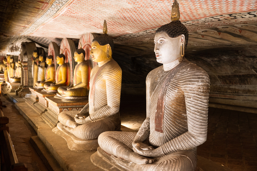 View of ancient Buddha statues and intricate ceiling murals inside the Dambulla Cave Temple Dambulla Central Province Sri Lanka.
