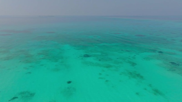 Aerial view of turquoise ocean and coral reefs.