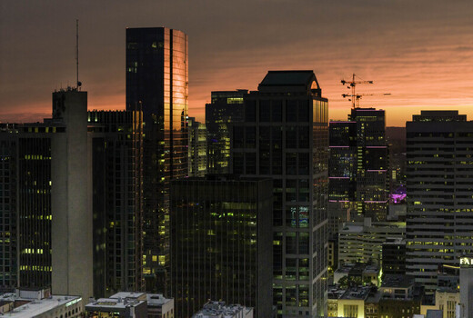 Aerial view of the downtown Nashville skyline at sunset featuring illuminated skyscrapers reflective glass facades and a vibrant orange sky over Nashville TN United States.
