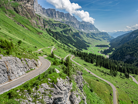 Aerial view of winding roads carve through verdant valleys beneath towering cliffs a symphony of green and grey Spiringen Uri Switzerland. Aerial view of winding roads carve through verdant valleys beneath towering cliffs a symphony of green and grey Spiringen Uri Switzerland.