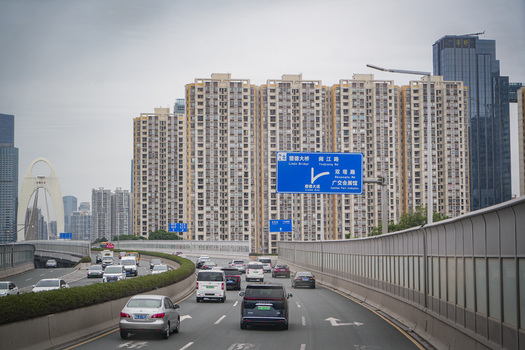 Guangzhou Guangdong Province China 23 February 2024 View of traffic on a multi lane urban highway with high rise residential buildings and the Liede Bridge in the background. Guangzhou Guangdong Province China 23 February 2024 View of traffic on a multi lane urban highway with high rise residential buildings and the Liede Bridge in the background.