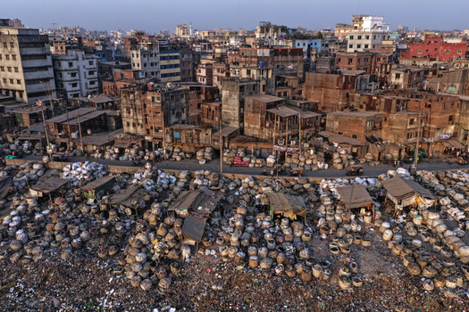 Aerial view of the Buriganga River waterfront featuring dense urban architecture and numerous sacks of goods stored in a market area in Dhaka Dhaka Division Bangladesh. Aerial view of the Buriganga River waterfront featuring dense urban architecture and numerous sacks of goods stored in a market area in Dhaka Dhaka Division Bangladesh.