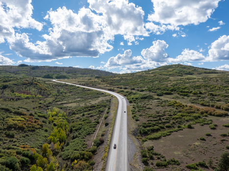Aerial view of a highway winding through the rolling hills and grassy landscape of Colorado United States. Aerial view of a highway winding through the rolling hills and grassy landscape of Colorado United States.