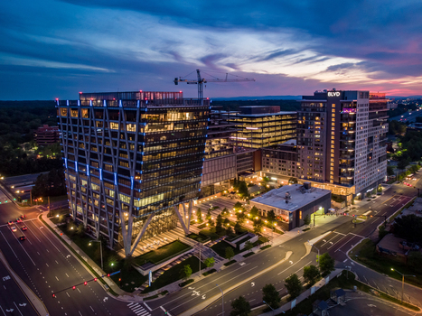 Reston Virginia United States 27 May 2020 Aerial view of modern office buildings and mixed use development at Reston Station at dusk featuring illuminated glass facades and streets. Reston Virginia United States 27 May 2020 Aerial view of modern office buildings and mixed use development at Reston Station at dusk featuring illuminated glass facades and streets.