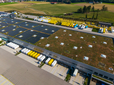 Aerial view of Logistikzentrum Allhaming with a green roof solar panels and loading docks with parked trucks in the rural landscape of Allhaming Oberosterreich Austria. Aerial view of Logistikzentrum Allhaming with a green roof solar panels and loading docks with parked trucks in the rural landscape of Allhaming Oberosterreich Austria.