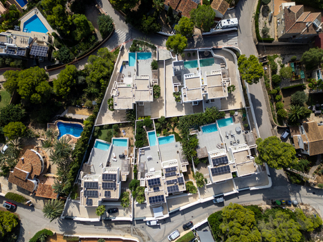 Aerial view of modern villas with private swimming pools and solar panels on rooftops in a residential area of Moraira Valencian Community Spain.