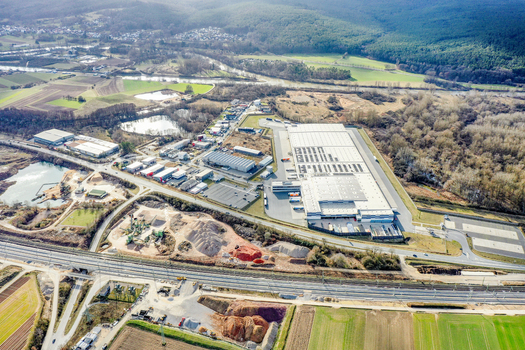 Aerial view of industrial warehouses and commercial buildings surrounded by green fields and forested hills in Buttenheim Bavaria Germany. Aerial view of industrial warehouses and commercial buildings surrounded by green fields and forested hills in Buttenheim Bavaria Germany.