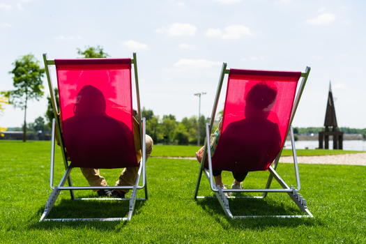 Bratislava Slovakia 09 May 2026 View of two people relaxing in bright pink deck chairs on a lush green lawn in a sunny park.