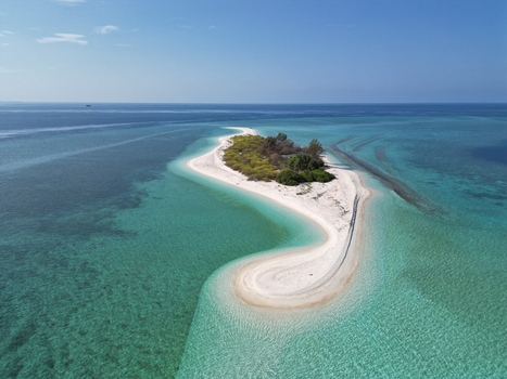 Aerial view of Pulau Ndaa a small crescent shaped island with white sand beaches surrounded by turquoise waters in Tomia South East Sulawesi Indonesia.