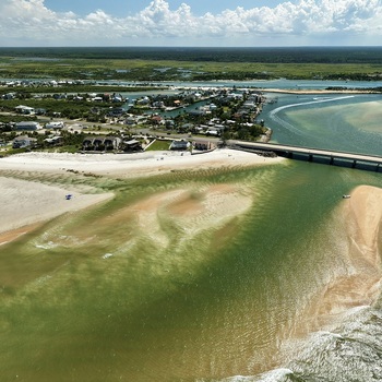 Aerial view of Matanzas Inlet featuring a bridge spanning the coastal waterway sandy beaches and residential homes along the shoreline in St. Johns County Florida United States. Aerial view of Matanzas Inlet featuring a bridge spanning the coastal waterway sandy beaches and residential homes along the shoreline in St. Johns County Florida United States.