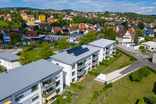 Aerial view of modern apartment buildings with solar panels on the roof and a residential neighborhood with green trees and hills Erlangen Bavaria Germany.