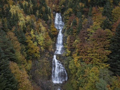 Aerial view of the waterfall in the Pyrenees surrounded by vibrant autumn foliage in Spain. Aerial view of the waterfall in the Pyrenees surrounded by vibrant autumn foliage in Spain.