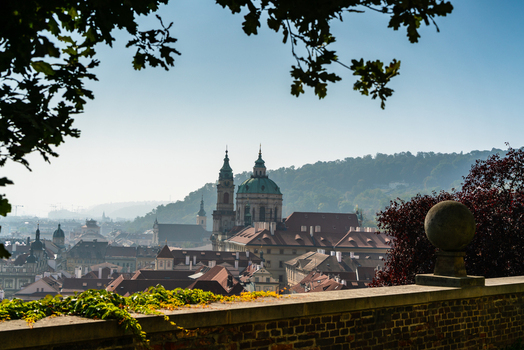 View of St. Nicholas Church with its green dome surrounded by historic red tiled rooftops and urban architecture in Prague Prague Czechia.