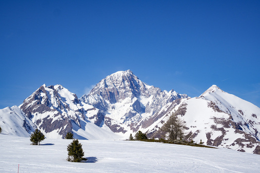Aerial view of the snow covered peaks of the Mont Blanc massif and ski slopes with lift infrastructure under a clear blue sky in La Thuile Valle d Aosta Italy. Aerial view of the snow covered peaks of the Mont Blanc massif and ski slopes with lift infrastructure under a clear blue sky in La Thuile Valle d Aosta Italy.