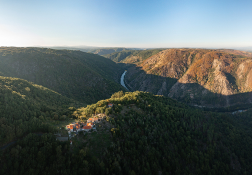 Aerial view of Monastery of Santo Estevo de Ribas de Sil nestled in the lush green Ribeira Sacra valley with the Sil River winding through the landscape in O Covelo Ourense Spain.