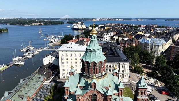 Aerial view of Uspenski Cathedral with its distinctive green domes and red brick architecture overlooking the harbor boats and city skyline in Helsinki Uusimaa Finland. Aerial view of Uspenski Cathedral with its distinctive green domes and red brick architecture overlooking the harbor boats and city skyline in Helsinki Uusimaa Finland.