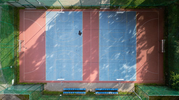 Aerial view of a colorful sports ground with blue and red hues surrounded by lush greenery and shadowed by trees Bydgoszcz Województwo kujawsko pomorskie Poland. Aerial view of a colorful sports ground with blue and red hues surrounded by lush greenery and shadowed by trees Bydgoszcz Województwo kujawsko pomorskie Poland.
