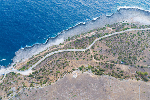 Aerial view of Riserva Naturale Orientata dello Zingaro coastline with a winding road rugged terrain and Mediterranean sea in San Vito Lo Capo Sicilia Italy. Aerial view of Riserva Naturale Orientata dello Zingaro coastline with a winding road rugged terrain and Mediterranean sea in San Vito Lo Capo Sicilia Italy.