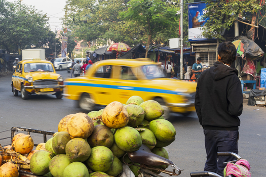 Kolkata India 05 December 2024 View of a vibrant street scene with yellow taxis blurring past a fruit vendor the scene infused with a dynamic urban energy. Kolkata India 05 December 2024 View of a vibrant street scene with yellow taxis blurring past a fruit vendor the scene infused with a dynamic urban energy.