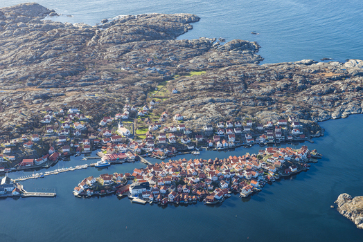 Aerial view of the village of Gullholmen featuring traditional red wooden houses rocky coastal terrain and a harbor in the archipelago Gullholmen Vastra Gotaland County Sweden.
