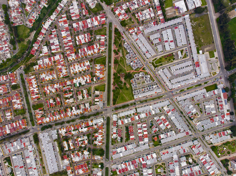 Aerial view of a residential neighborhood featuring a central triangular park surrounded by dense housing with red and white rooftops in Tlaquepaque Jalisco Mexico. Aerial view of a residential neighborhood featuring a central triangular park surrounded by dense housing with red and white rooftops in Tlaquepaque Jalisco Mexico.