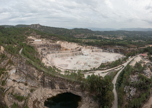 Aerial view of Cantera Porrino showing the large open pit granite quarry with stone blocks machinery and surrounding pine forests in O Porrino Pontevedra Spain. Aerial view of Cantera Porrino showing the large open pit granite quarry with stone blocks machinery and surrounding pine forests in O Porrino Pontevedra Spain.