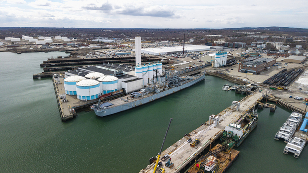 Aerial view of the Fore River Bridge casting a shadow over the water contrasting with the industrial buildings and tanks Quincy Massachusetts United States.