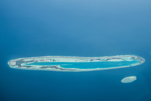 Aerial view of a tropical island surrounded by turquoise waters and fringed with white sand a jewel amidst the deep blue sea Flight from Male to Hanimaadhoo island Maldives.